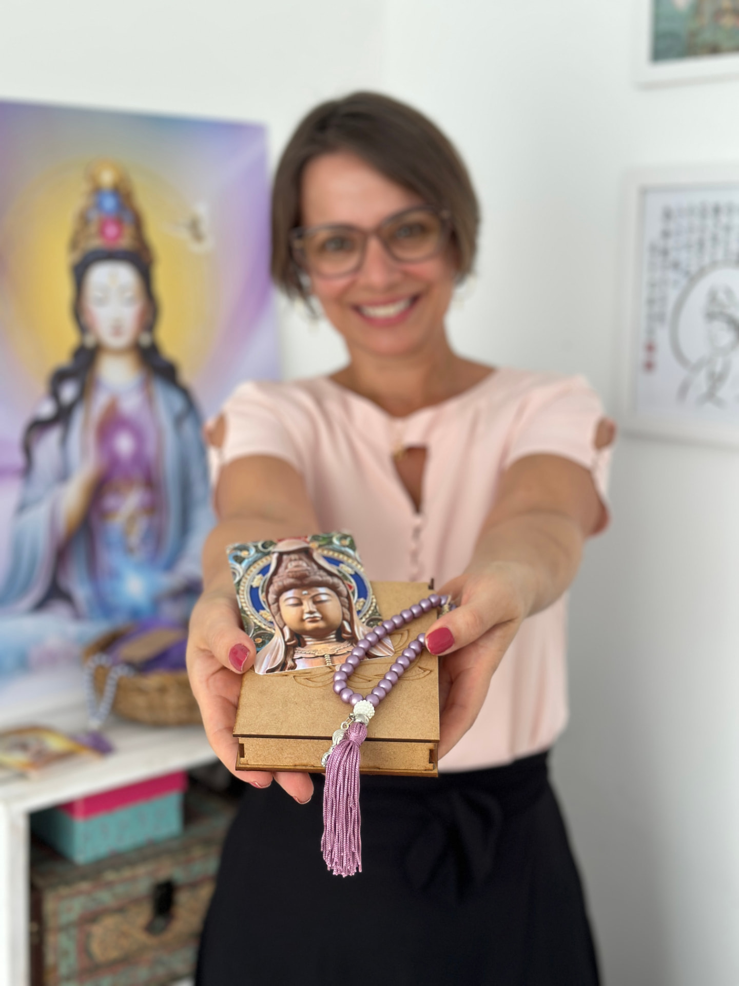 Michele segurando a caixa do Oráculo Terapêutico de Kuan Yin e o japamala de 33 contas