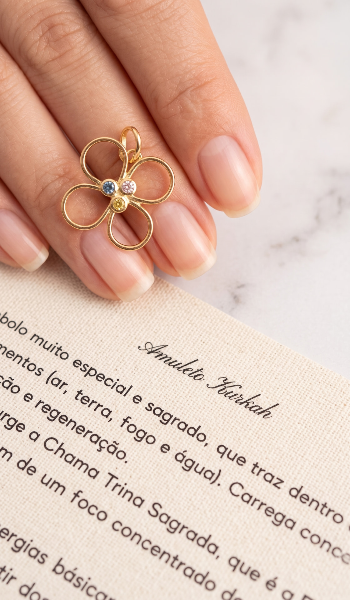 Amuleto Kurkah com detalhes nas cores azul, rosa e amarela, sobre o texto impresso que acompanha a peça