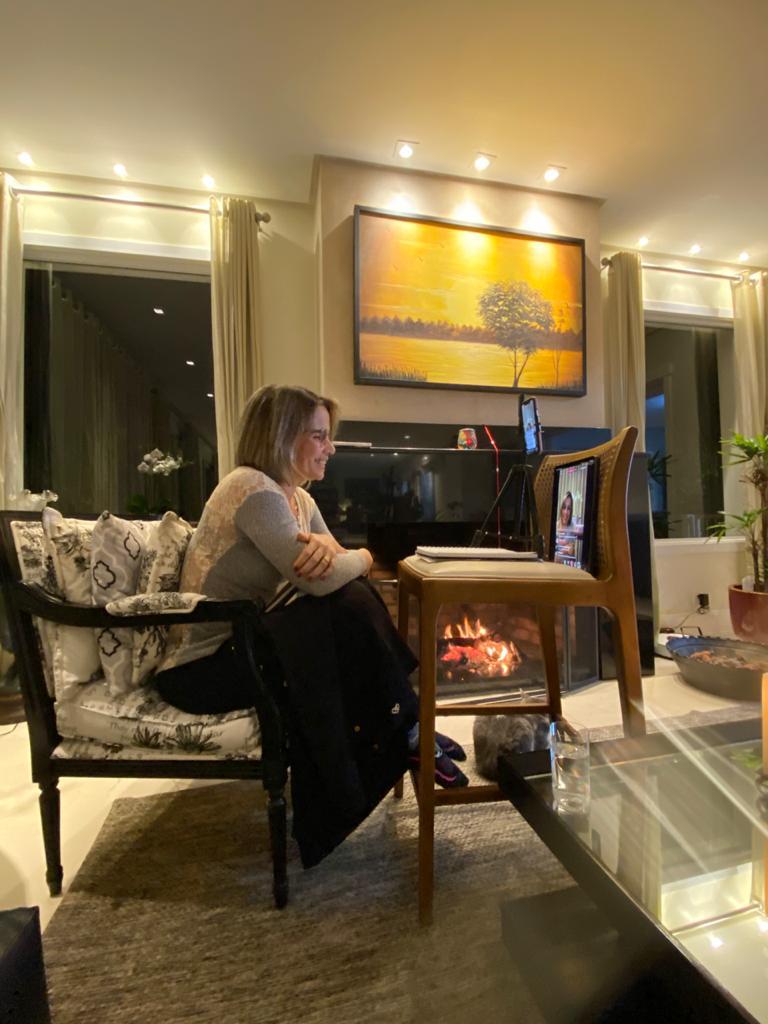 Michele durante a live de lançamento do livro Karuna Reiki, sentada em sua sala diante da lareira